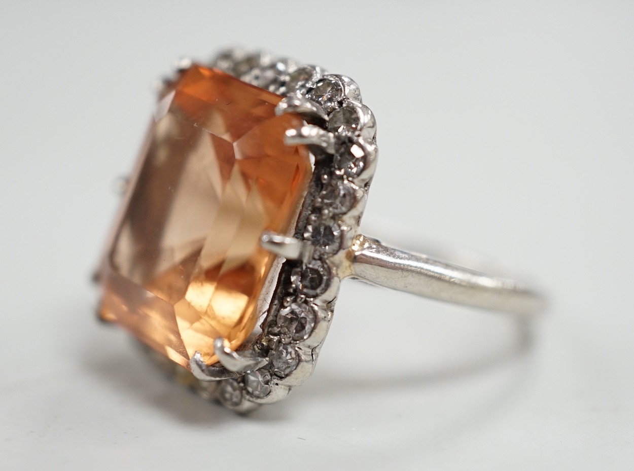A white metal and emerald cut orange/peach topaz set dress ring, with diamond set border, size I/J, gross weight 6.1 grams.